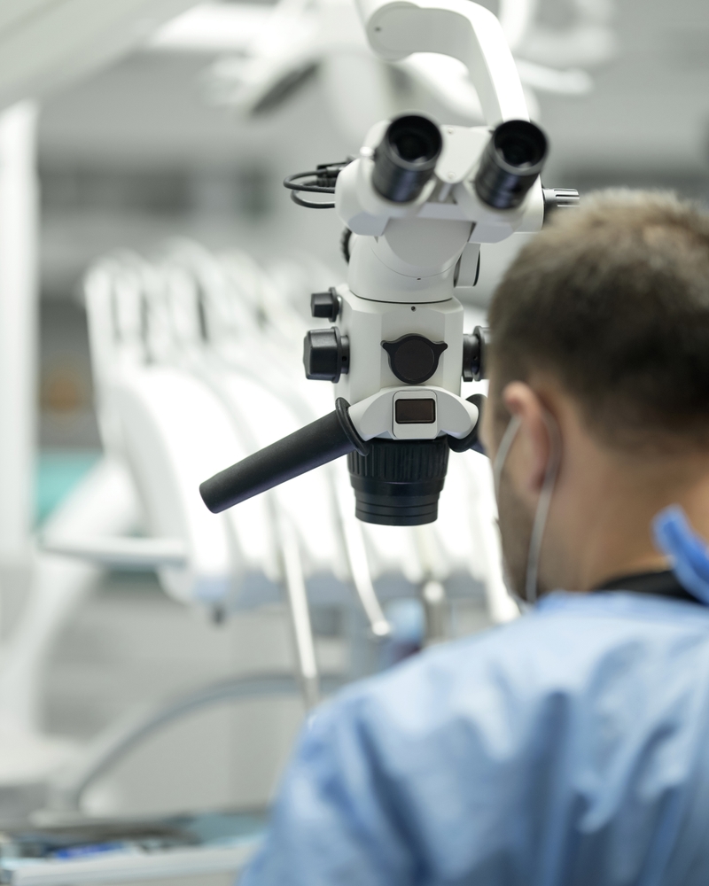 Dentiste effectuant un retraitement endodontique complexe sous microscope au cabinet du Dr Teasdale, Paris 16.